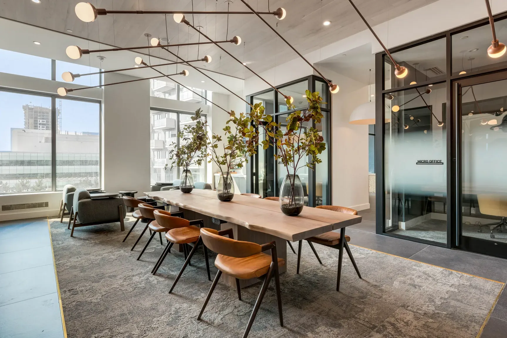 Spacious modern meeting room with a long wooden table, brown leather chairs, and large windows.