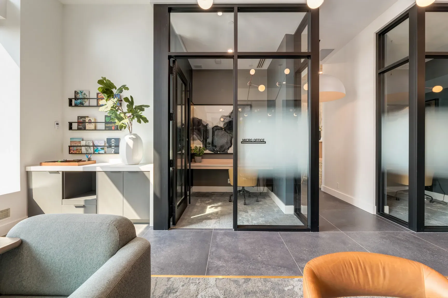 Modern office interior with glass-walled meeting rooms and a cozy seating area.