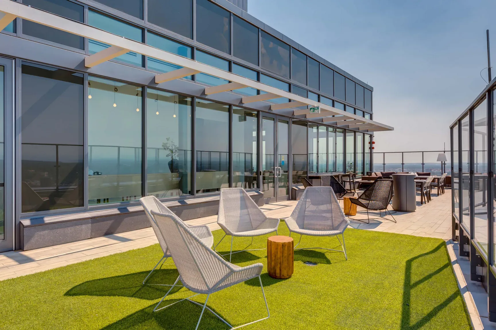 Rooftop patio with artificial grass, modern lounge chairs, and a city view.