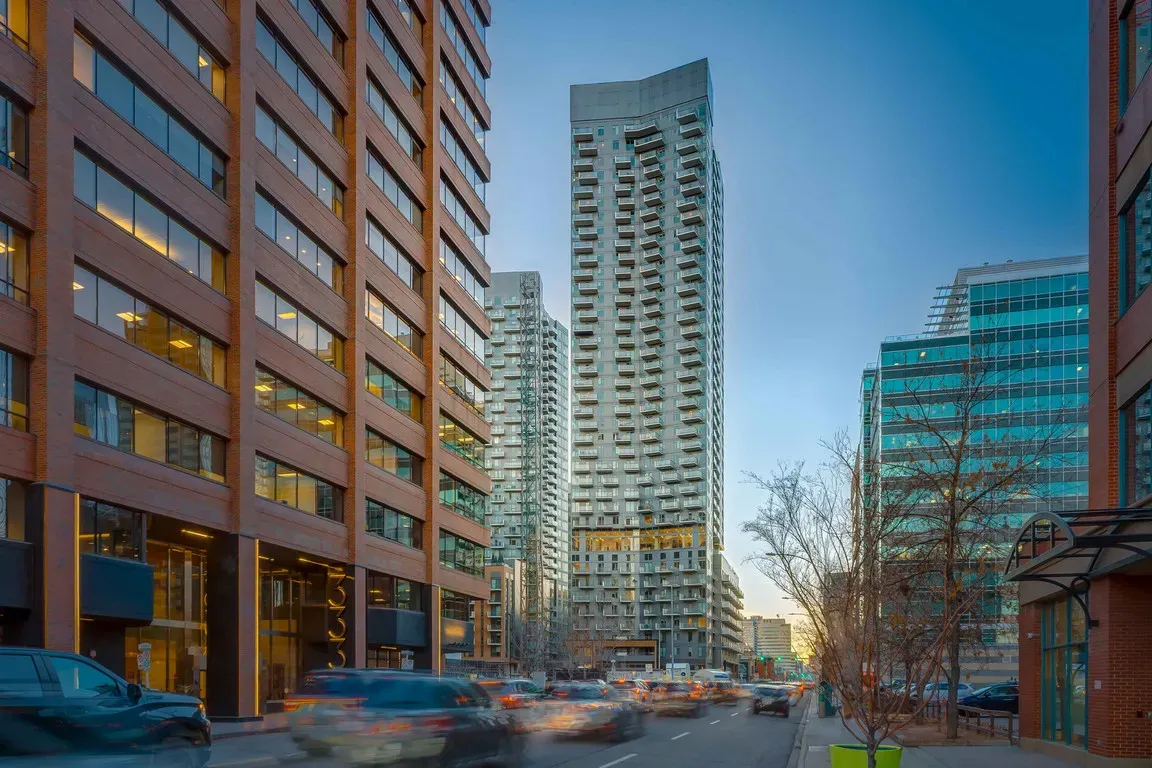 A busy city street lined with modern skyscrapers and cars in motion under a clear sky.